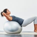 Shot of a young woman exercising using a fitness ball